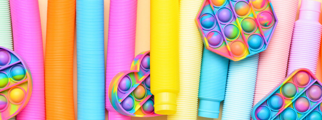 Colorful Pop Tubes and Pop it fidget toys, top view. Banner for design - obrazy, fototapety, plakaty