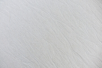 Obraz premium Sand background and texture. Wet beach sand texture after low tide. Sand with wave print. Ripple on the beach sand.