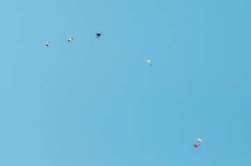 A group of parachutists in a clear sky with colored bright parachutes.