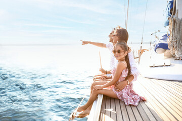 Happy young family resting on yacht - obrazy, fototapety, plakaty