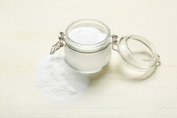 Jar with baking soda on white wooden background