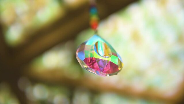 satisfying scene of a crystal that has chakra colors representing meditation spirituality and relaxation hanging from the celing blurry backround depth of field slow motion