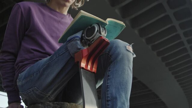Man with leg prosthesis reads textbook sitting on stairs