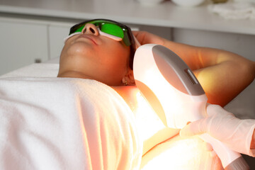 Latina woman with skin treatment, Hispanic doing laser hair removal underarms, dermatology clinic in Costa Rica. Skin treatment, acne and hair removal. Copy space for advertising and blurred backgroun