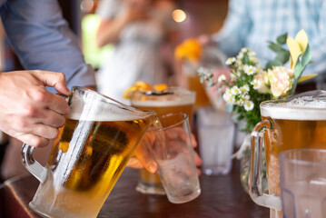 Closeup of a man's hand pouring beer from a pitcher