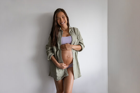 Happy Asian pregnant woman portrait at home. Pregnancy maternity underwear, model wearing organic cotton clothes, loose shirt and undies clothes for comfort