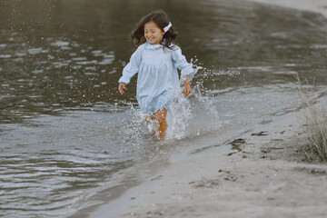 Adorable curly baby girl splashing in a river