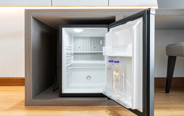 Black mini small fridge refrigerator under the frame wooden counter in hotel resort bedroom - obrazy, fototapety, plakaty