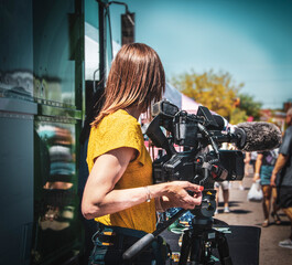 Woman professional videographer by van at street festival with camera and microphone ready copy
