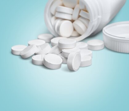 Different pills and antibiotics are spilled on the table from a medical jar