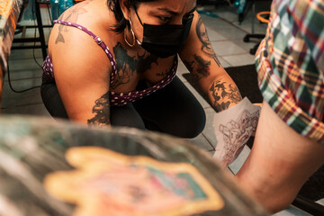 Latina tattoo artist putting a sketch of a tattoo on her client's leg in a studio in Managua, Nicaragua.
