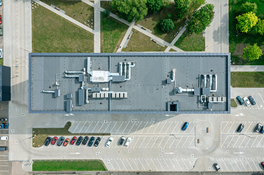 aerial top view of office building with empty parking lot. rooftop with installed pipes of ventilation system.