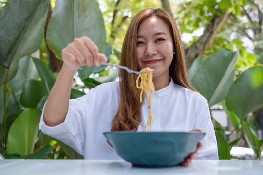 Portrait image of a beautiful young woman eating spaghetti in the outdoors restaurant