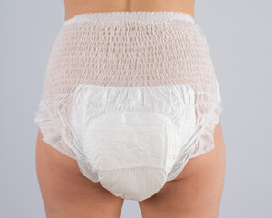 Rear view of a Woman in adult diapers on a white background. Incontinence problem. 