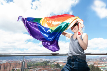 young gay man proudly waves the LGBT flag under a sunny sky. High quality photo