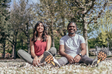 portrait of two interracial sport friends sitting in park