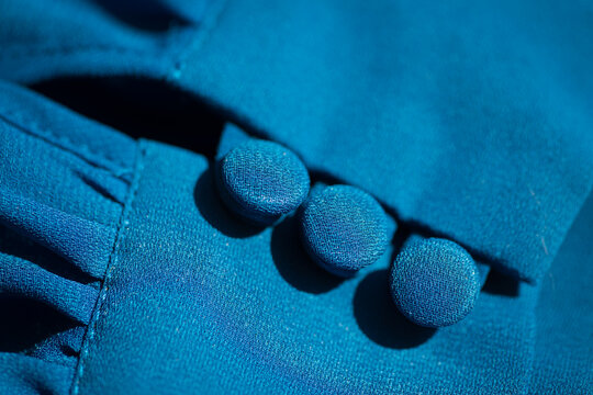 close up of a blue sleeve of dress with buttons