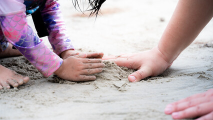 Family travels to the sea during summer holidays. Close Up father and daughter hands are building...