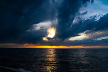 Naklejka na ściany i meble Black clouds over the sea at sunset time