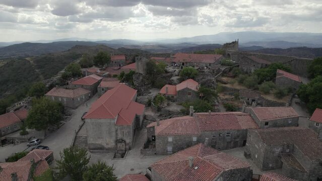 Drone flying over roofs of granite rural houses in Sortelha village with mountains in background, Portugal. Aerial forward
