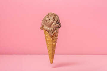 funny creative concept of hovering in air wafer cone with chocolate ice cream scoop on pink...