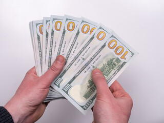 Male hands counting cash bills of 100 dollars on a white background top view