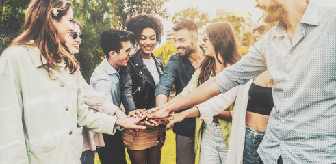 Multicultural group of young friends joining hands together outdoors - concept of people unity,...