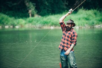 Fisherman fishing on a rever. Relaxed fisher man with a fishing rod on a summer day.