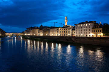 Florence waterfront with Ponte Vecchio bridge over Arno river at night in Italy
