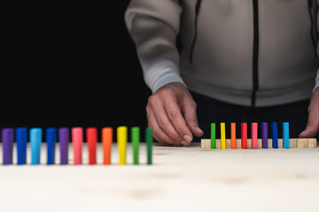 Conceptual photo of hands preparing a row of domino stones.
Domino effect with colored stones and copyspace