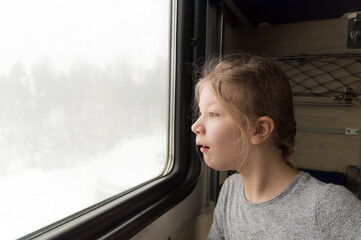the girl looks out the train window with surprise.
