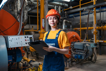 Concept of a industrial manufactory. A female smiling worker in uniform and helmet with a folder...