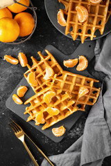 Homemade ginger waffles with tangerines. Delicious Christmas pastries on a black background	