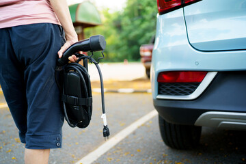 Unrecognizable woman holding the portable EV emergency charging adapter.
