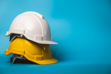 White and yellow hard safety helmet hat for safety project of workman as engineer or worker, on  blue background.