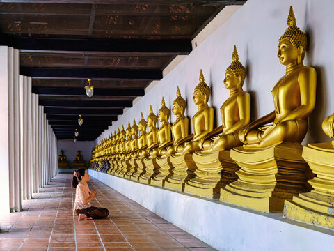 Asian woman sitting on floor pray and worship to Golden Buddha statue