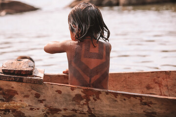 Indian child from the Asurini tribe in Brazil, playing inside a canoe in the Amazon River. 2010.