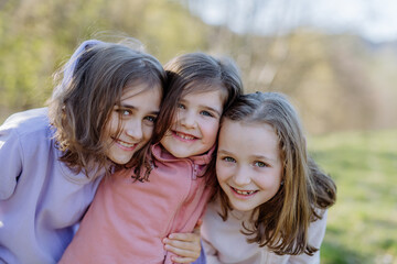 Fototapeta premium Three little sisters looking at camera in spring nature together.