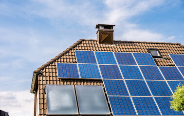 Solarkollektoren zur Erzeugung von Strom und Warmwasser auf Hausdach - obrazy, fototapety, plakaty