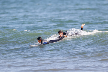 サフィンで波に乗ろうとする子供を手助けするお父さん
