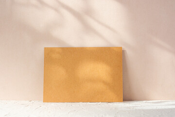 blank kraft paper poster with pampass grass in wood vase on cement table at peach wall