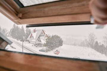 Roof window view of a severe winter weather view in the mountains. Concept of winter vacation during winter holidays in cozy cottage