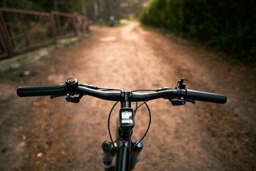 Top view of mountain bike handlebar and blurred cross country forest road. Concept of extreme activity on the woods trails.