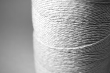 Roll of thread with blurred grey background. Rolled up twine also known as spool.