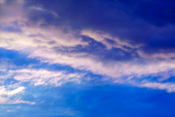 Summer sky. White clouds in the blue sky. Heaven and infinity. Beautiful bright blue background. Light cloudy, good weather. Curly clouds on a sunny day