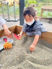 マスクをして砂場で遊ぶ女の子