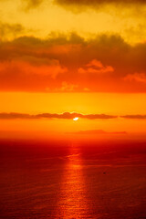 Fototapeta na wymiar Red sun in the clouds. Colorful sunset in the evening sky. Great dramatic view. Clouds illuminated by the setting sun. Amazing sky panorama. Meditative calmness and greatness