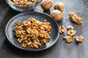 Peeled walnut kernels on plate on black table.