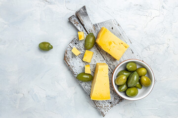Homemade hard cheese with olives on old wooden board light background. banner, menu, recipe place...