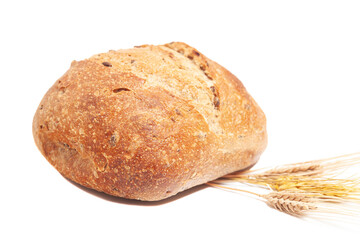 Loaf of round bread with wheat ears isolated on white background.